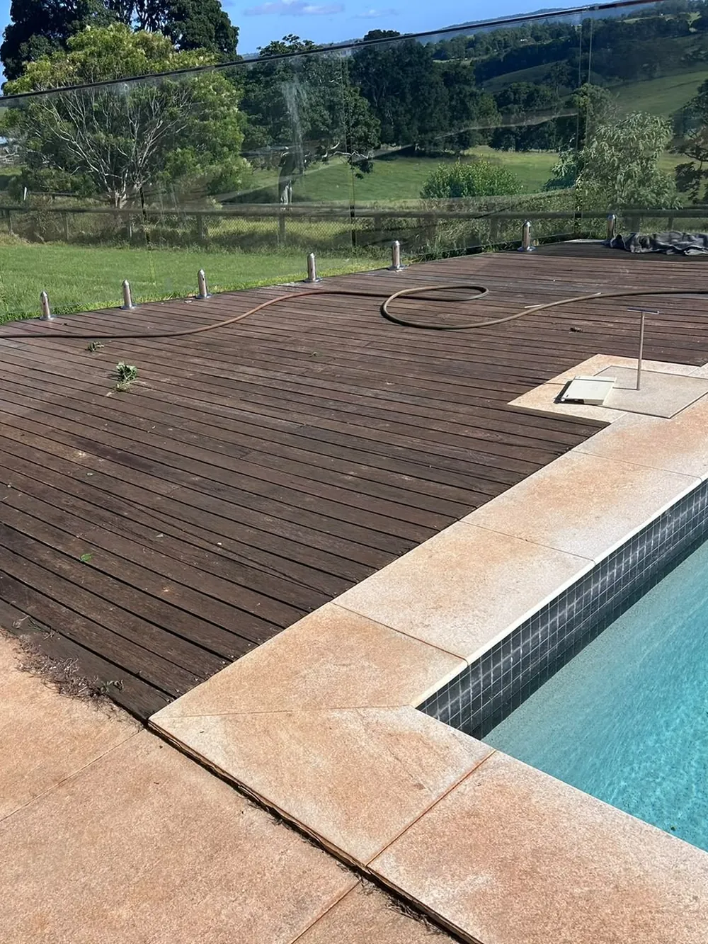 Before: faded, weathered grey pool deck with weeds in the gaps