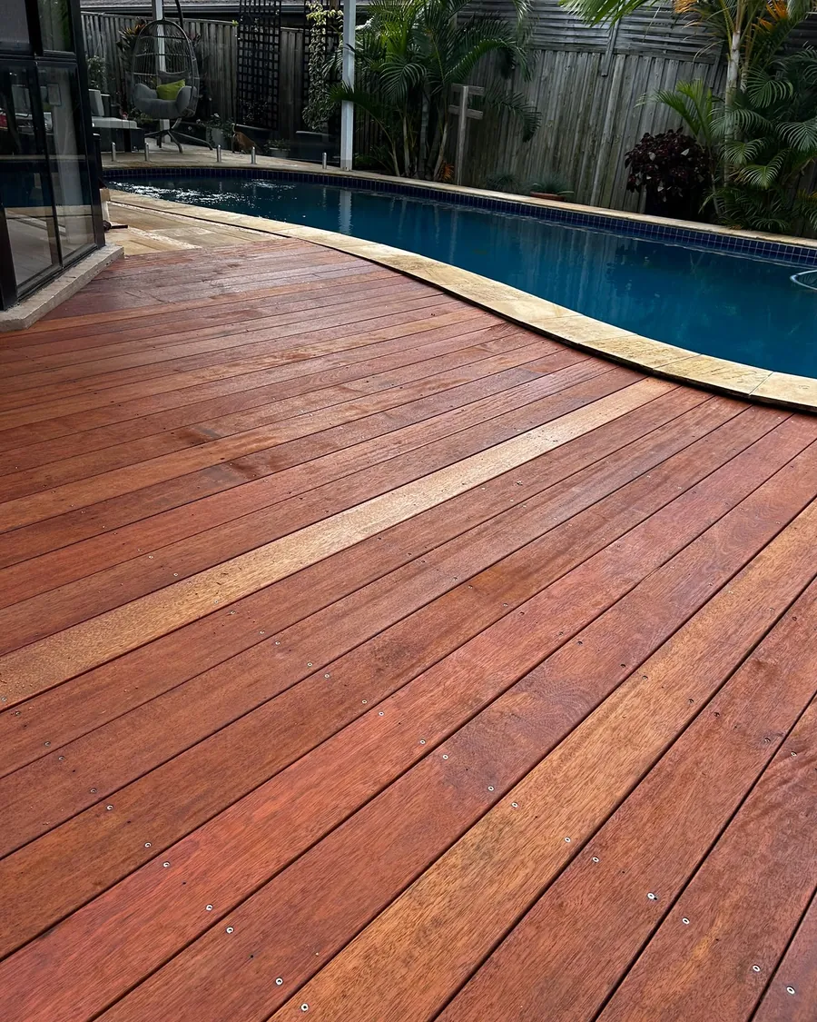 Freshly oiled merbau deck curving around a kidney-shaped pool